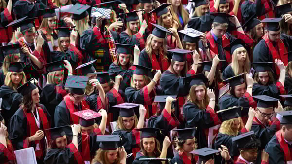 Eine große Gruppe Absolventen der Ardscoil Phadraig in roten Talaren versammelt sich zur Abschlussfeier.