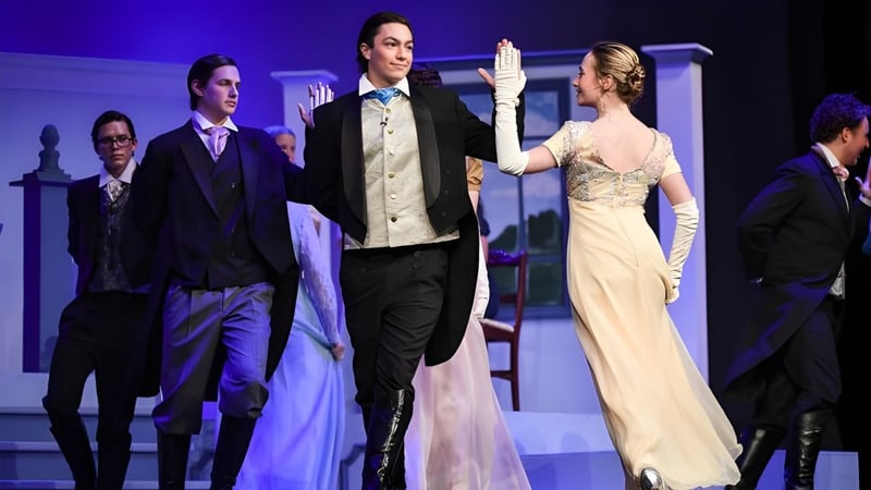 Schüler und Lehrkräfte der Arendell Parrott Academy stehen bei einer formellen Veranstaltung auf der Bühne vor blauem Bühnenlicht.