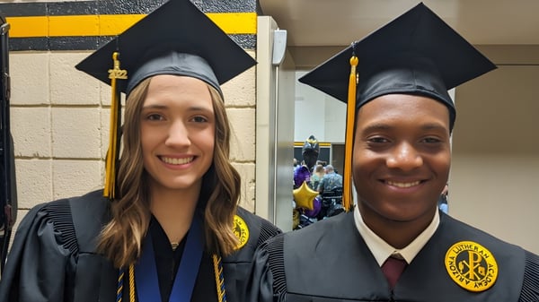 Zwei Absolventen in Talaren und Hüten posieren auf dem Campus der Arizona Lutheran Academy für ein Foto.