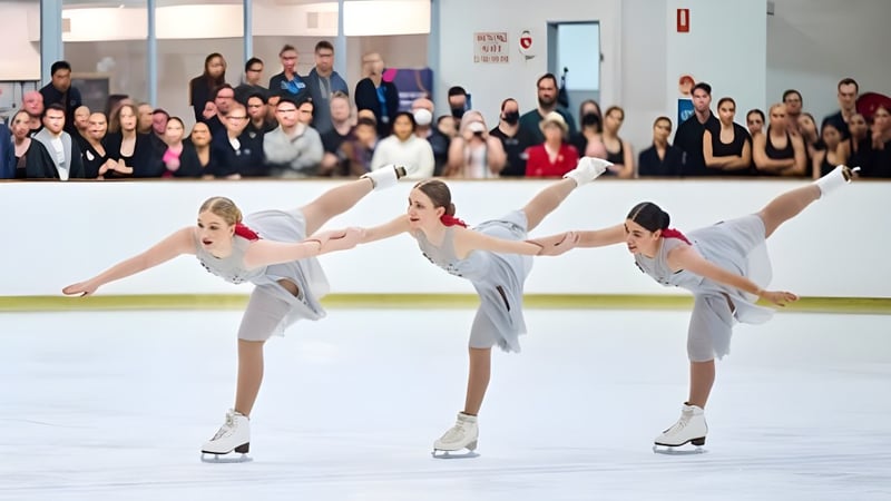 Schülerinnen der Armadale Senior High School führen gemeinsam eine synchronisierte Eiskunstlauf-Performance auf der Eisbahn vor Publikum auf.