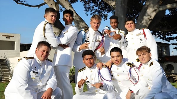 Eine Gruppe von Schülerinnen und Schülern der Army and Navy Academy posiert im Freien vor Bäumen und einem Gebäude.