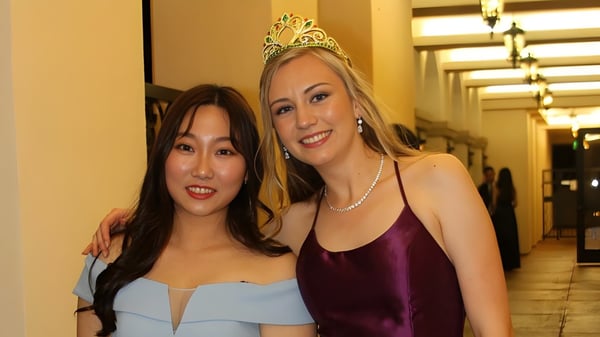 Zwei Schülerinnen der Arroyo Pacific Academy posieren im Flur mit dekorativen Leuchten im Hintergrund.