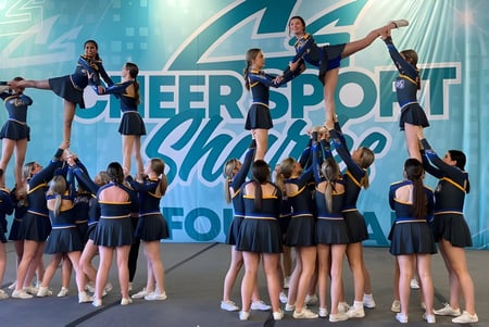 Eine Gruppe Cheerleader der Ascension Collegiate führt eine akrobatische Routine bei der Cheersport Showdown Aufführung auf der Bühne auf.