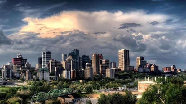 Dramatische Stadtsilhouette mit hohen Wolkenkratzern und bewölktem Himmel vor grüner Landschaft nahe Ascension Collegiate.