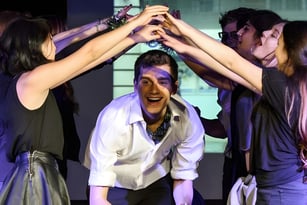 Eine Gruppe Schülerinnen und Schüler des Ashbourne College feiert gemeinsam mit erhobenen Händen vor dunklem Hintergrund.