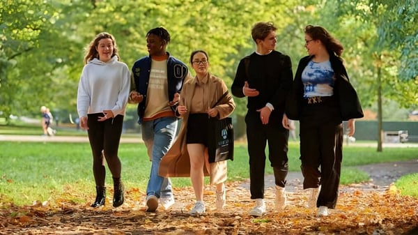 Eine Gruppe Schülerinnen und Schüler des Ashbourne College geht gemeinsam auf einem von grüner Natur umgebenen Weg spazieren.
