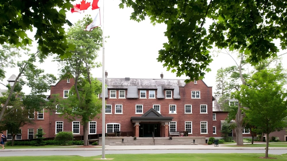 Das Backsteingebäude mit markantem Eingang und kanadischer Flagge auf dem Campus des Ashbury College.