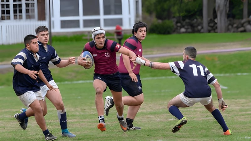 Schüler des Ashbury College spielen ein Rugby-Match auf dem Feld vor Schulgebäuden.