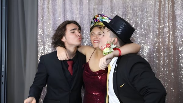 Zwei Personen umarmen sich vor einem schimmernden silbernen Hintergrund auf dem Campus der Ashdale Secondary College.