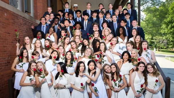 Eine Gruppe formell gekleideter Schülerinnen und Schüler versammelt sich vor dem Backsteingebäude der Asheville School.