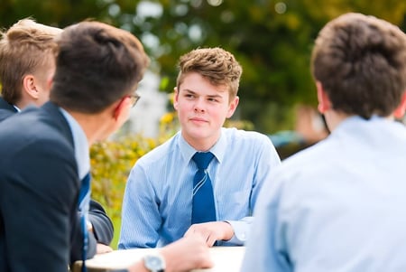 Eine Gruppe Schüler der Ashford School unterhält sich vor einer grünen und blumigen Kulisse.
