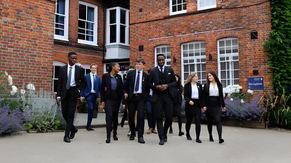 Eine Gruppe von Personen geht gemeinsam vor einem Backsteingebäude auf dem Gelände der Ashford School.
