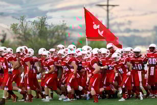 Eine Gruppe Fußballspieler in roten Uniformen mit roter Fahne auf dem Sportfeld des Ashland School District.