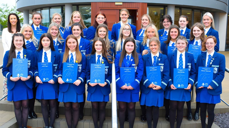 Eine Gruppe von Schülerinnen in blauen Uniformen steht vor einem modernen Gebäude der Assumption Grammar School.