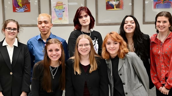 Eine Gruppe Schülerinnen steht gemeinsam in einem Innenraum auf dem Campus der Athens Christian School vor bunter Wandkunst.