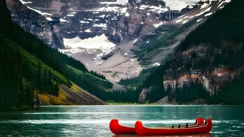 Ein rotes Kanu liegt auf einem klaren See vor schneebedeckten Bergen auf dem Gelände der Athens District High School.
