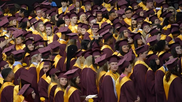 Absolventen der Atherton State High School versammeln sich während der Abschlussfeier in ihren roten und gelben Talaren.