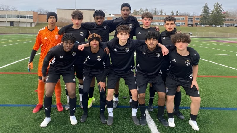 Eine Gruppe von Schülerinnen und Schülern des Athlete Institute posiert auf dem Fußballfeld vor einem Schulgebäude.