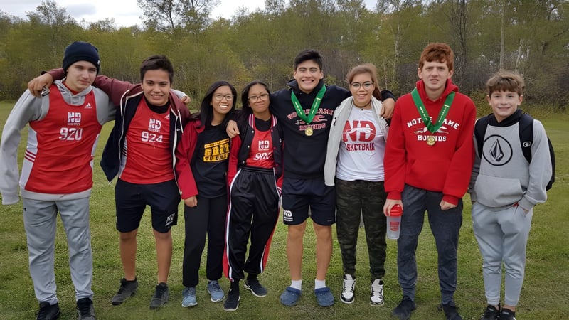 Eine Gruppe von Schülerinnen und Schülern steht together im Wald auf dem Campus des Athol Murray College of Notre Dame.