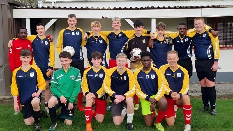 Eine Gruppe junger Fußballspielerinnen und Fußballspieler posiert vor einem Gebäude auf dem Campus des Athy College.