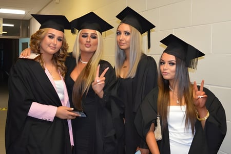 Vier Schülerinnen in Abschlusskleidung posieren gemeinsam im Flur des Athy College.