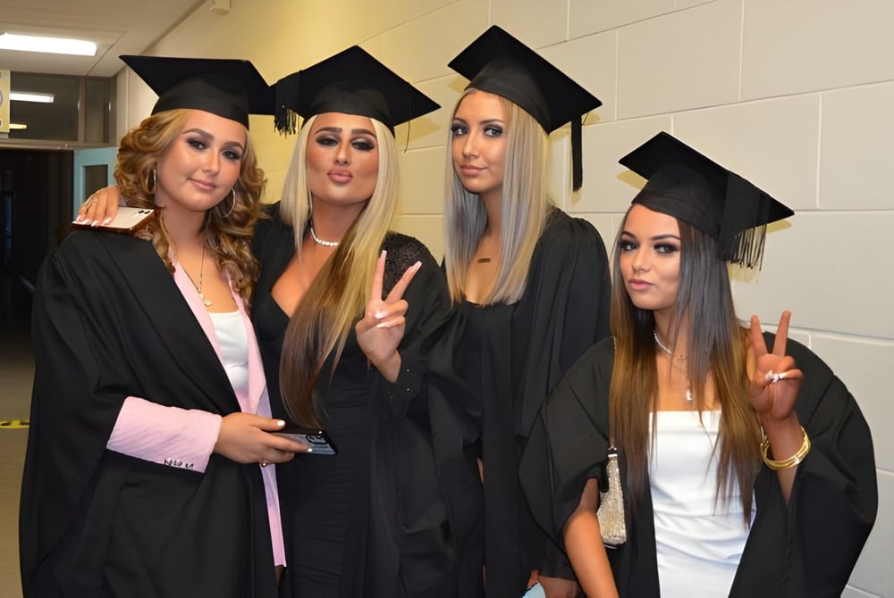 Vier Schülerinnen in Abschlusskleidung posieren gemeinsam im Flur des Athy College.