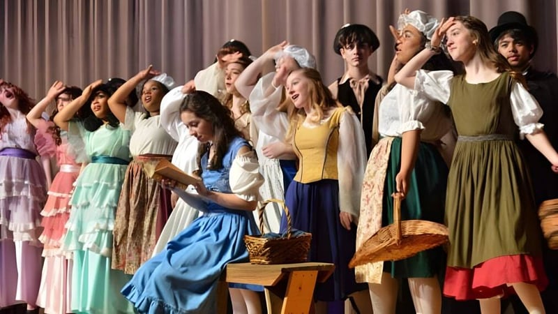 Eine Gruppe von Frauen in bunten Retro-Kleidern posiert auf der Bühne der Atlantic Shores Christian School.