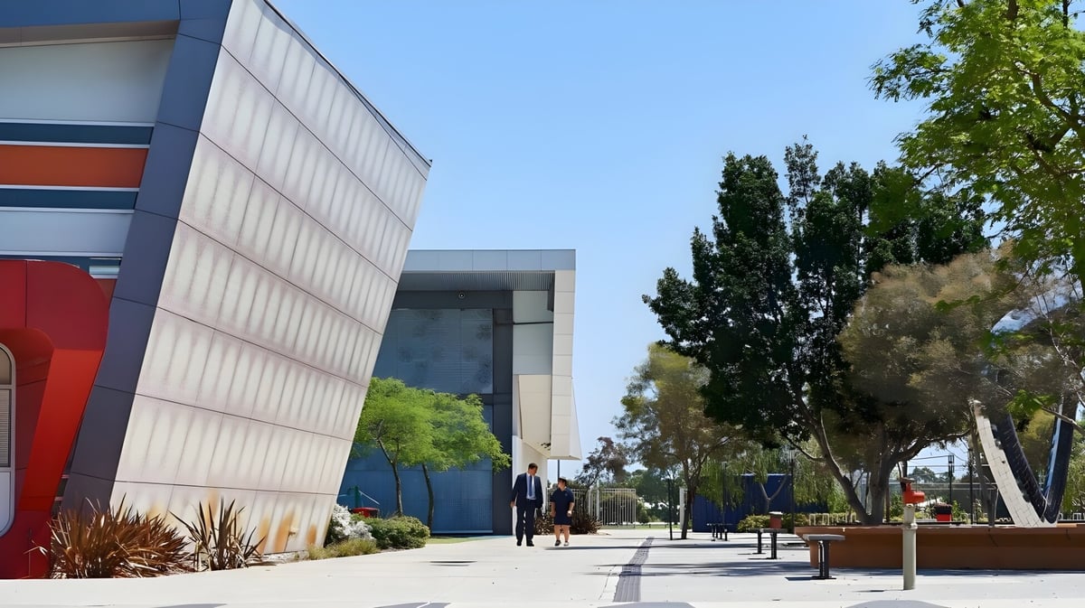 Das moderne Gebäude des Atwell College ist von grünen Anlagen umgeben und steht vor einem klaren blauen Himmel.