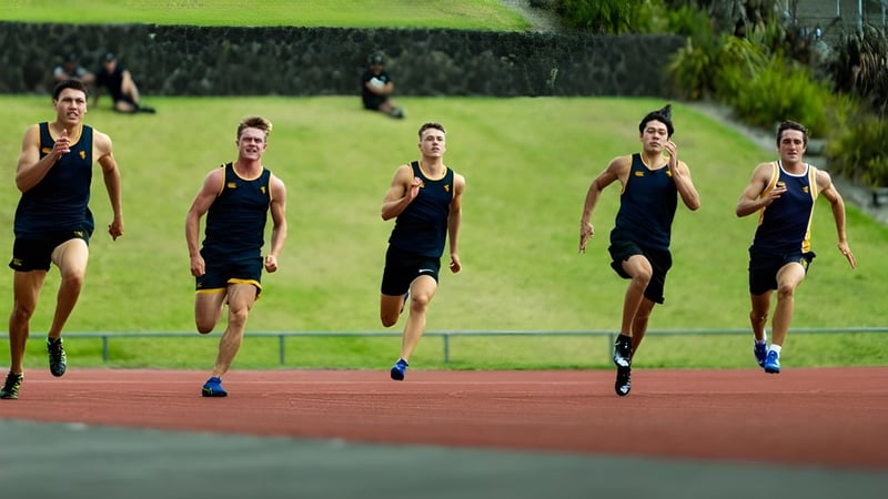 Eine Gruppe von Athleten in schwarzen Uniformen läuft auf der Laufbahn der Auckland Grammar School.