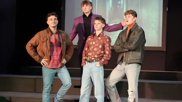 Vier Schülerinnen und Schüler der Austin Friars School stehen gemeinsam auf einer Bühne vor dunklem Hintergrund.
