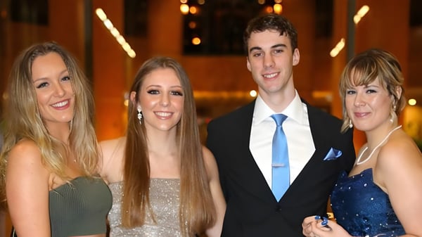 Vier Personen, zwei Frauen und zwei Männer, posieren zusammen vor dekorativem Hintergrund auf dem Campus der Australian Science and Mathematics School.