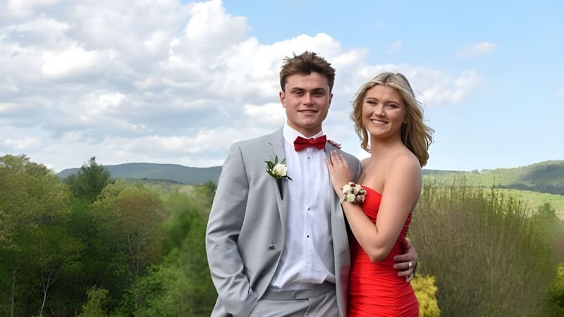 Ein junges Paar steht in einer grünen Landschaft vor Bergen auf dem Gelände der Avon Old Farms School.