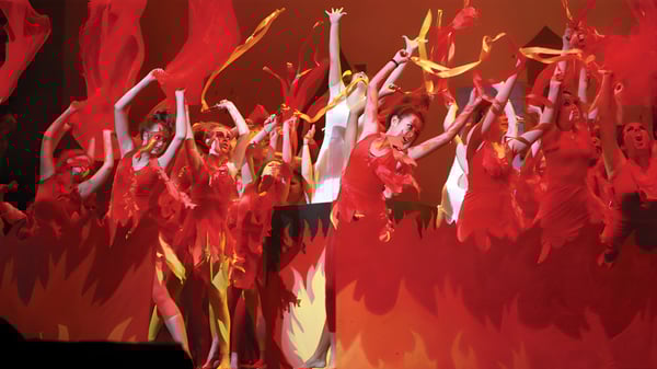 Eine Gruppe von Tänzerinnen und Tänzern des Avondale College führt eine dynamische Performance mit roten und gelben Kostümen auf.