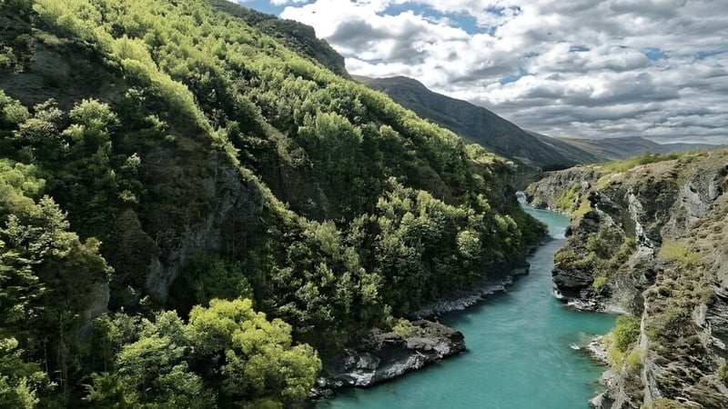 Eine bewaldete Berglandschaft mit einem türkisen Fluss, der sich durch steile Felsen schlängelt.