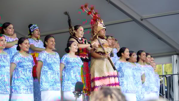 Schülerinnen der Avonside Girls' High School führen einen Auftritt in traditioneller hawaiianischer Kleidung auf einer Bühne vor grauer Wand auf.
