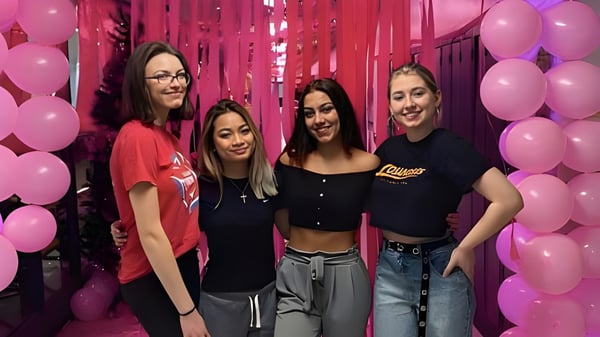 Vier Schülerinnen posieren zusammen in einer festlichen Szene mit bunten Luftballons auf dem Campus der A.Y. Jackson Secondary School.