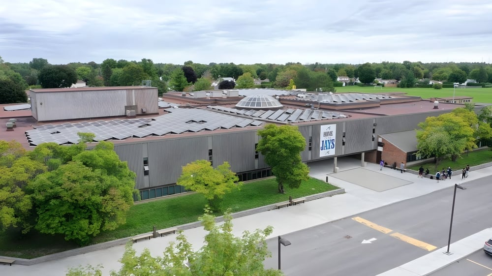 Das moderne Hauptgebäude der A.Y. Jackson Secondary School ist von grüner Landschaft und Bäumen umgeben.