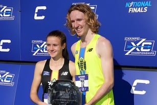 Zwei Athleten stehen vor dem Banner der National XC Championships auf dem Campus von Baccalieu Collegiate.