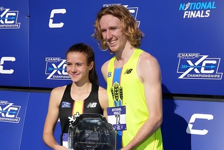 Zwei Athleten stehen vor dem Banner der National XC Championships auf dem Campus von Baccalieu Collegiate.