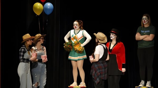 Eine Gruppe von Schülerinnen und Schülern des Baccalieu Collegiate steht in bunten Kostümen auf einer Bühne mit Luftballons im Hintergrund.