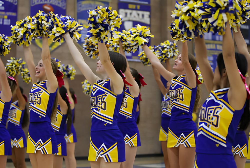 Cheerleader der Bakersfield Christian School heben im Stadion ihre blauen und gelben Pompons während einer Veranstaltung.