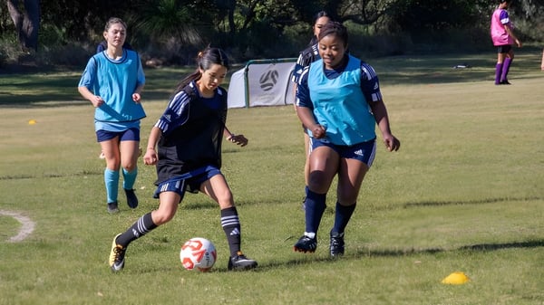 Weibliche Fußballspielerinnen der Balga Senior High School trainieren auf einem Rasenplatz während einer Sportveranstaltung.