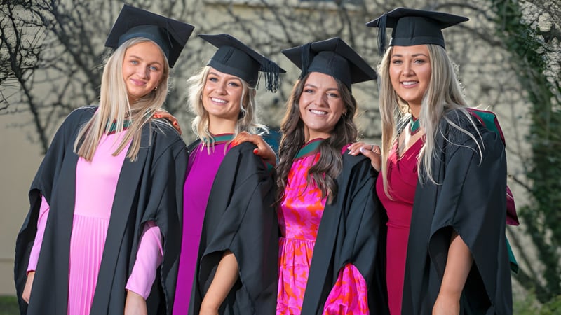 Vier Absolventinnen der Balla Secondary School stehen gemeinsam im Freien in ihren Abschlussroben.