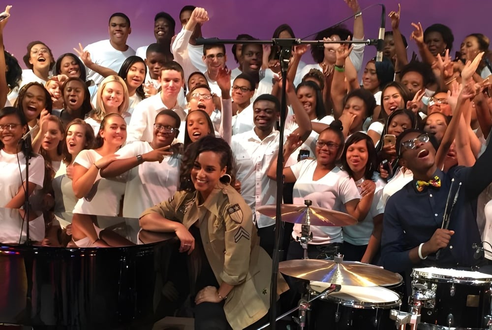 Schüler der Balla Secondary School spielen gemeinsam auf der Bühne vor einem violetten Hintergrund Musikinstrumente.