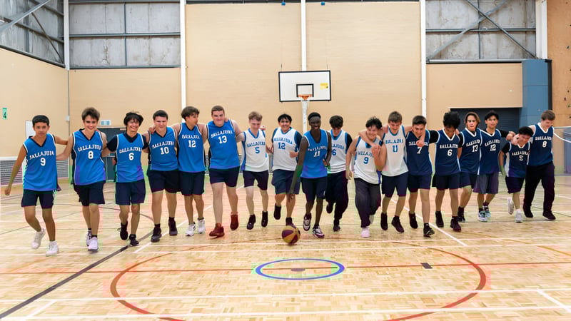 Eine Gruppe von Schülerinnen und Schülern spielt Basketball auf dem Sportplatz des Ballajura Community College.