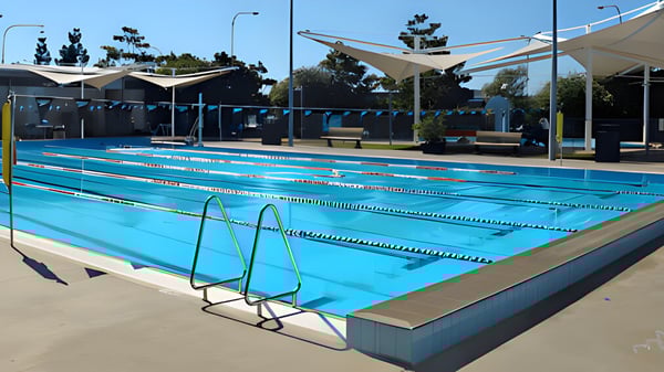 Das große Schwimmbecken im Außenbereich des Ballajura Community College ist von schattigen Sitzbereichen und Bäumen umgeben.