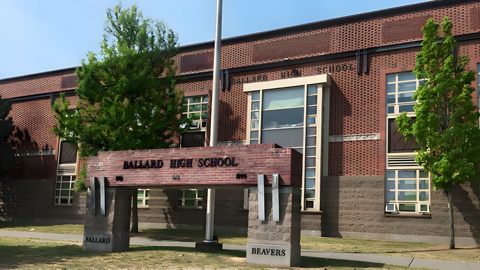 Das Backsteingebäude der Ballard High School ist von Bäumen und Laternen im Vordergrund umgeben.