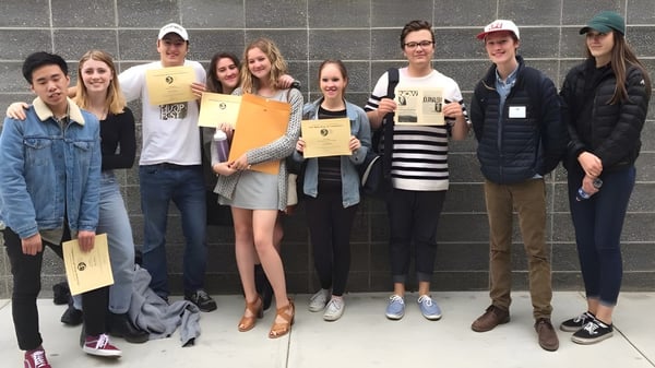 Eine Gruppe Schülerinnen und Schüler der Ballard High School steht vor einer gefliesten Wand und hält Zertifikate.