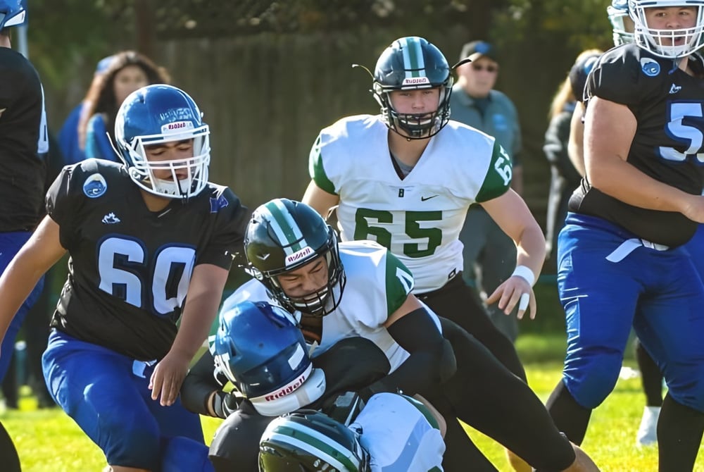 Schüler der Ballenas Secondary School spielen in Uniform Fußball auf einem Rasenfeld mit Bäumen im Hintergrund.