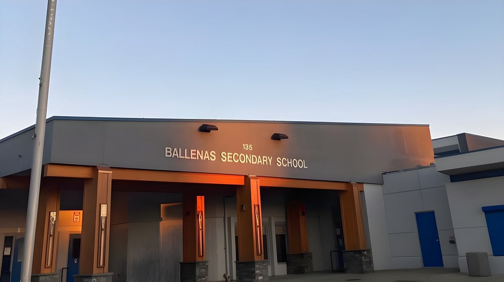 Das moderne Gebäude der Ballenas Secondary School mit einem gut sichtbaren Schild vor klarem blauem Himmel.